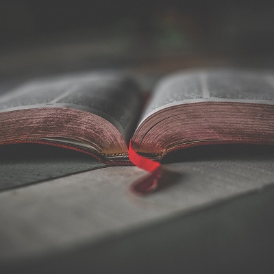 Artistic picture of a religious book, open at one of the middle pages, left on a table. Represents religious education twilight sessions