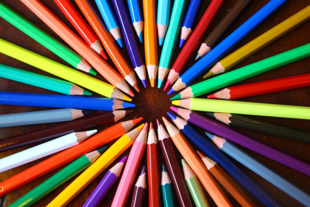 Multi-coloured crayons all lay in a circle in a rainbow pattern.